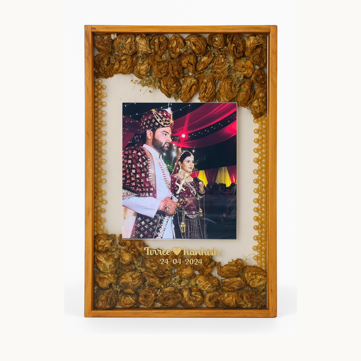 Polished teakwood frame with golden garland flower bands above and below a couple photo with stamp style edge