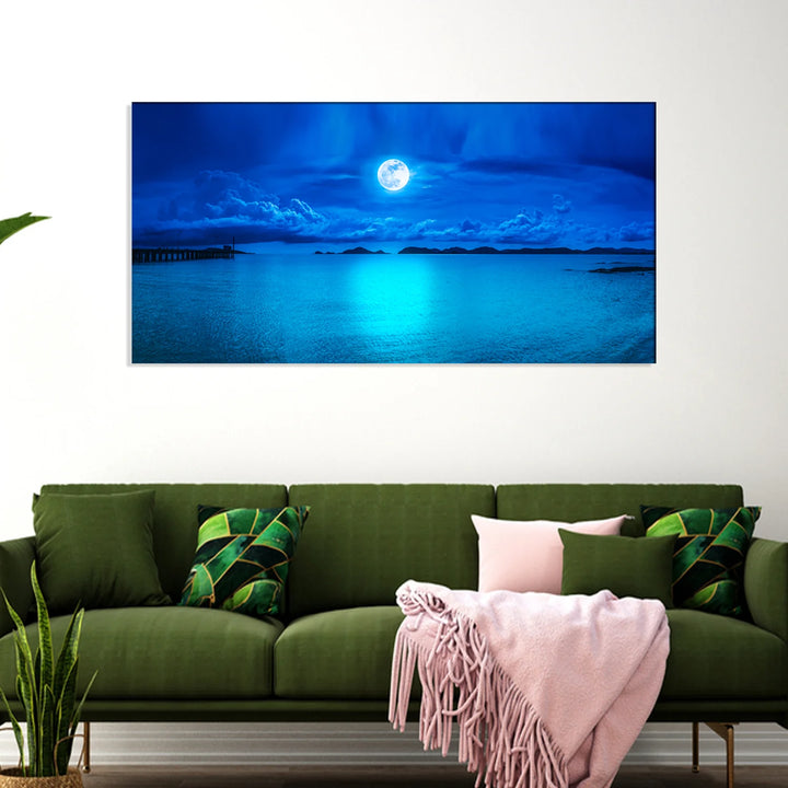 Full moon low over a deep blue sea with light on the water, canvas painting above a green sofa