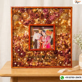 Square wooden double frame packed with maroon, pink and gold varmala roses around an inner framed couple photo