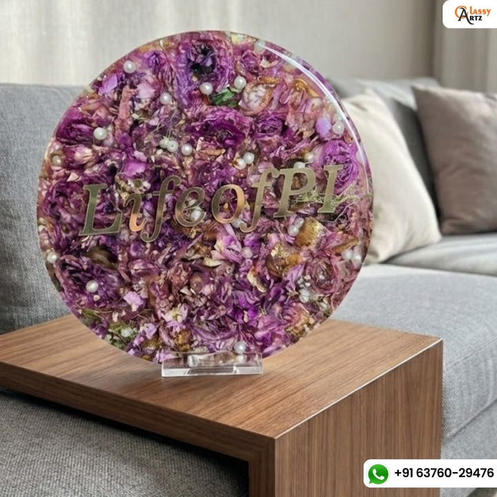 8 inch round varmala planter with mauve petals, gold script text and greenery on a wooden side table