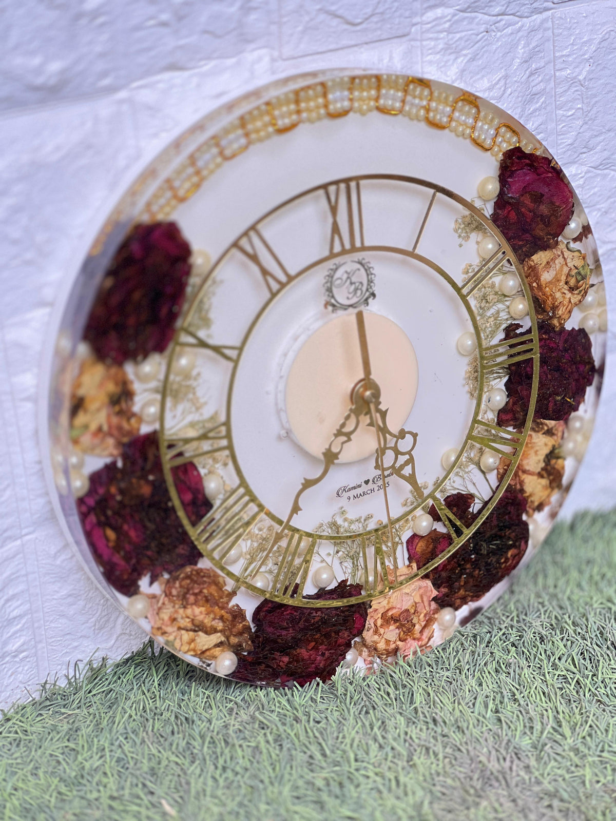Resin 12 inch clock with In 3/4 part covered with flowers , upr part with pearl 2 lines white base in middle pink colour with logo in center Varmala Preservation