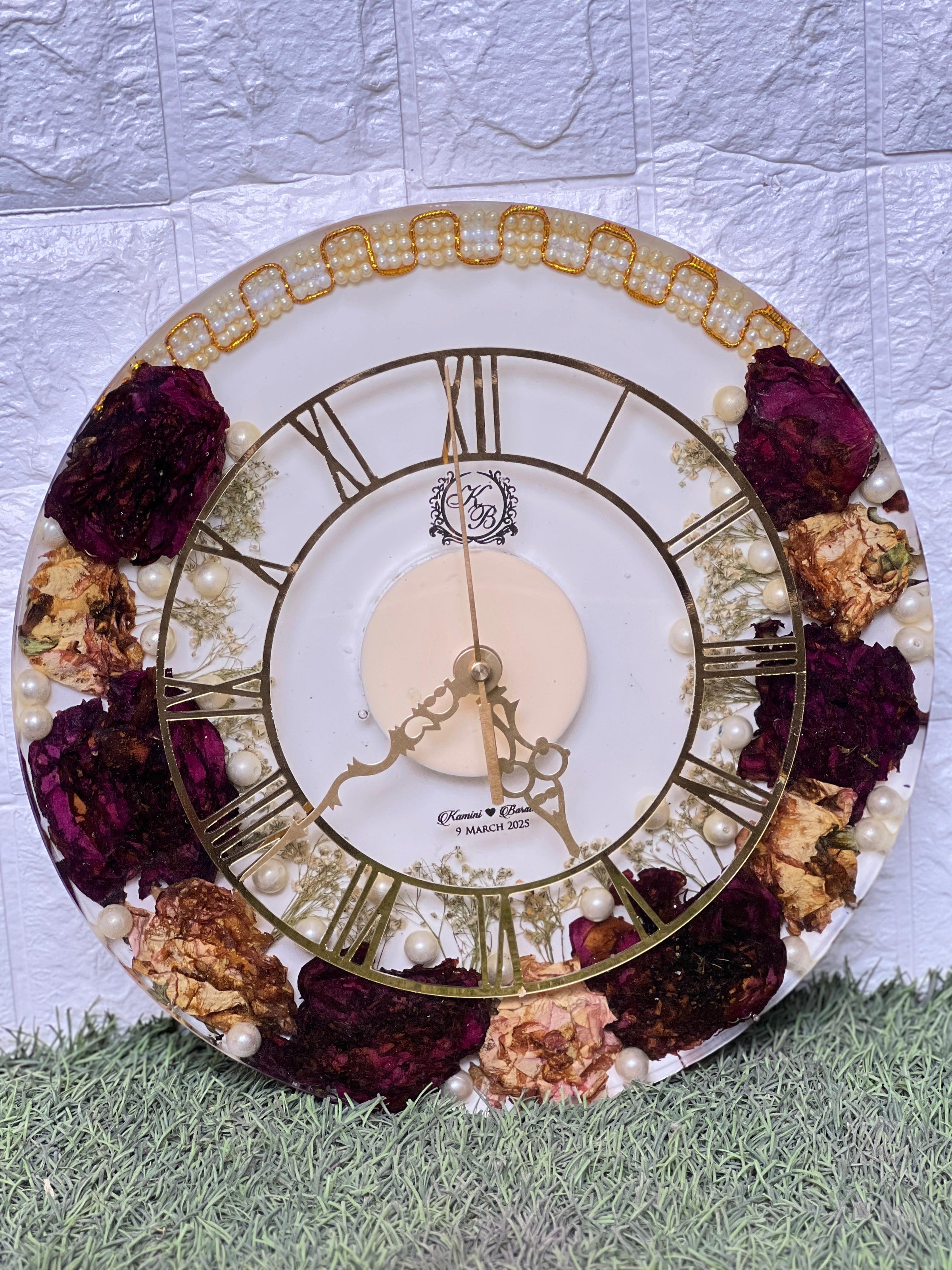 Resin 12 inch clock with In 3/4 part covered with flowers , upr part with pearl 2 lines white base in middle pink colour with logo in center Varmala Preservation